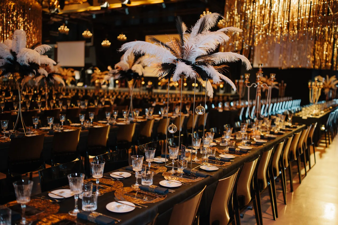 Gala-Tafel mit weißen Federn und goldenem Vorhang im HANGAR